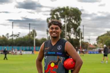 Photo of SAASTA student Seth holding a football at the Aboriginal Power Cup footy carnival