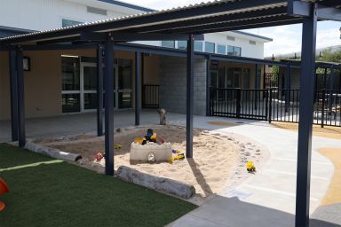 School infrastructure and footpaths surround a sandpit play area