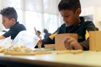 A student using wooden counting blocks in a maths lesson