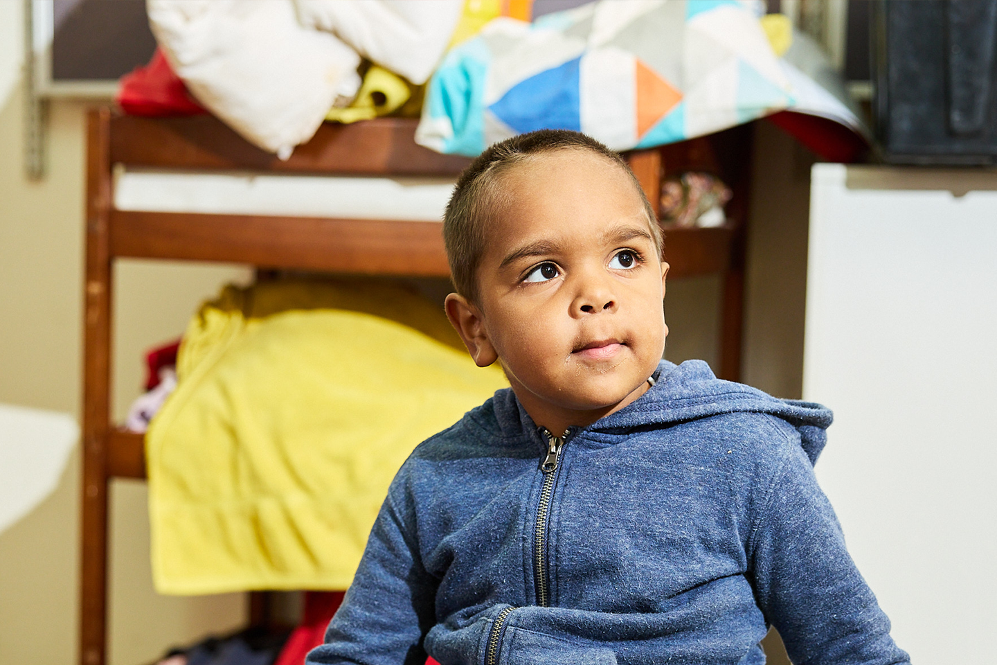 Photo of Aboriginal preschool student in blue jumper looking off into the distance
