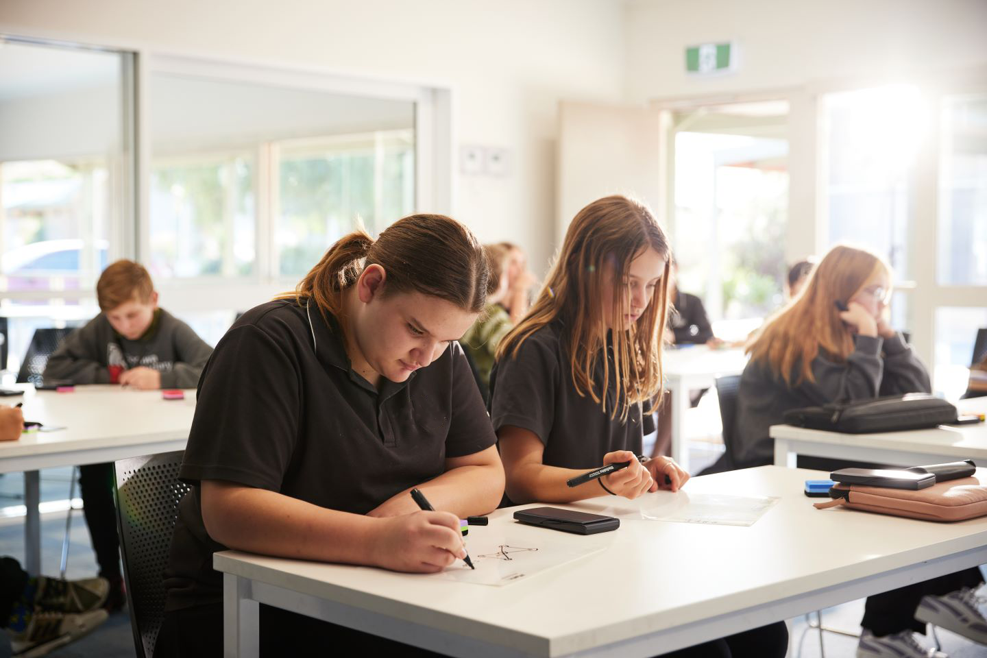 Two students, at their desks learning and writing