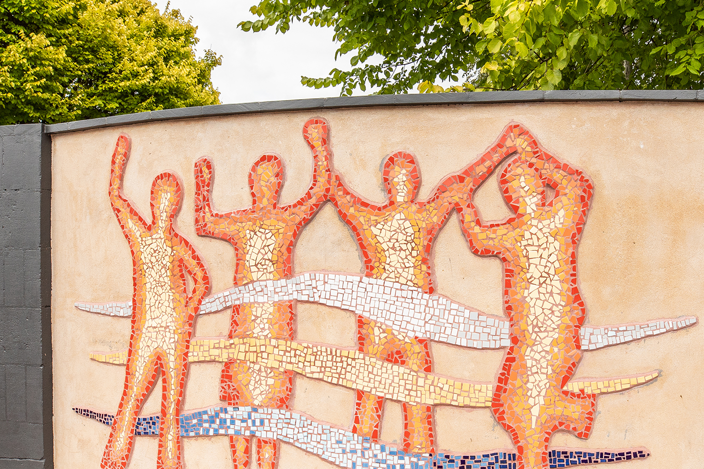 Photo of mosaic tile mural of four people holding hands in celebration