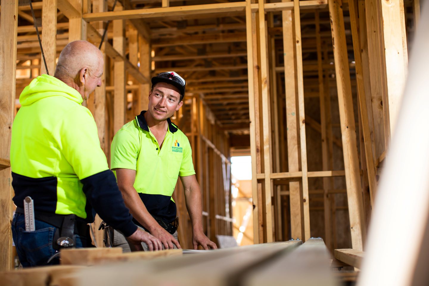 Two men, standing, and talking, while completing a task