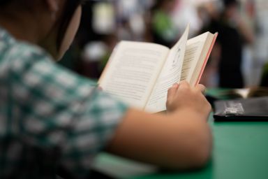 Student sitting at a table reading a book