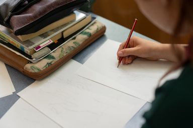Student using a pencil to draw on a piece of paper.