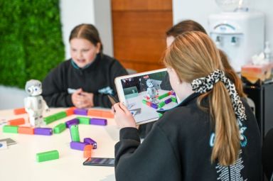 Three students, in a class, holding an iPad, filming