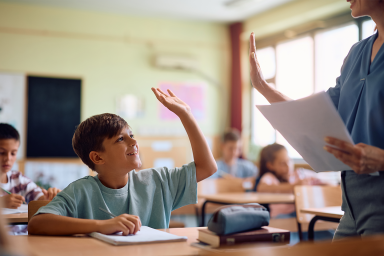 Photo of primary school student high-fiving teacher in class
