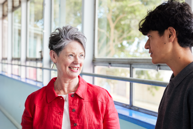 Photo of school leader in red jacket talking with senior student