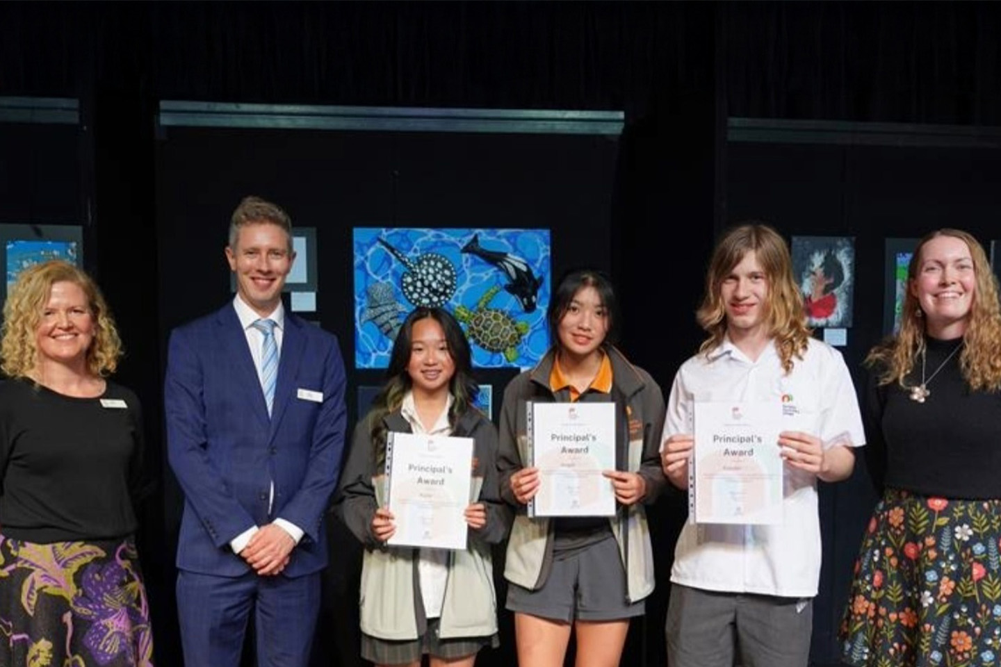 Three students holding certificates, along with three teachers who are all standing side-by-side