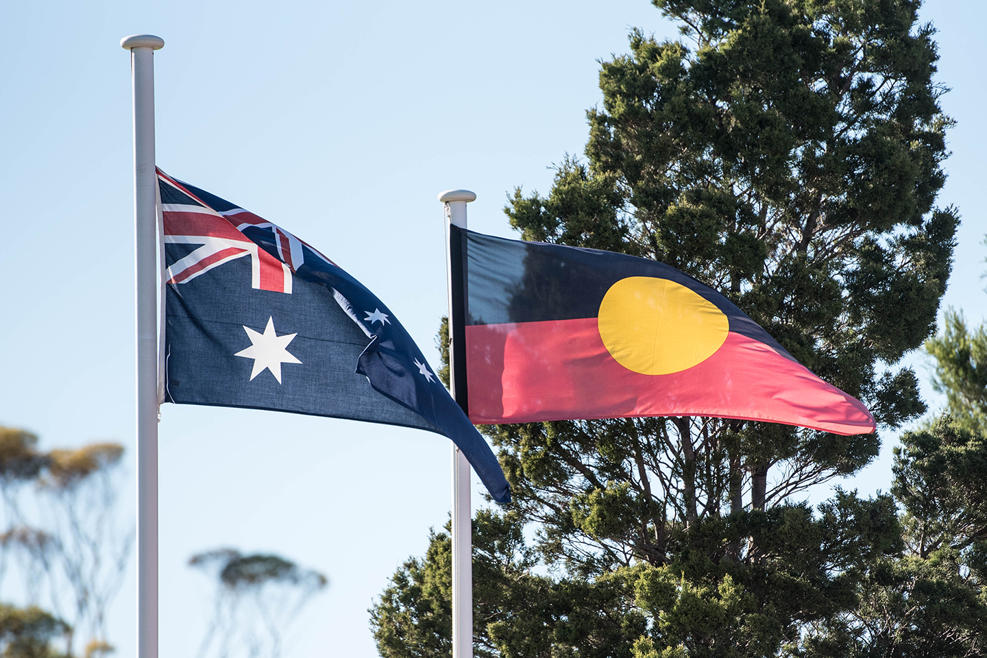 Photo of Australian and Aboriginal flags flying next to each other out the front of a school