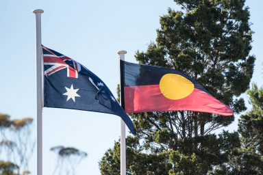 Photo of Australian and Aboriginal flags flying next to each other out the front of a school