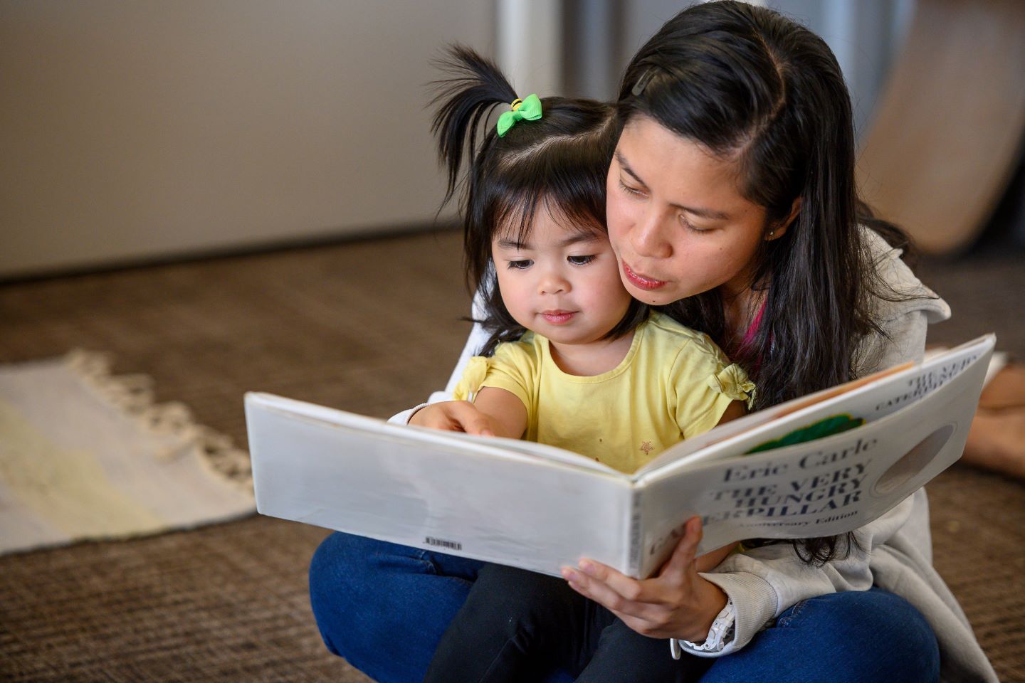 Parent and child, sitting on the floor reading 