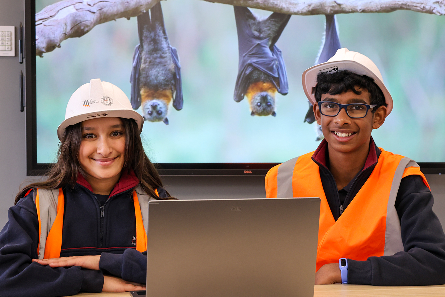 Photo of two students from The Heights Primary School wearing hi-vis and hard-hats while researching bat project brief