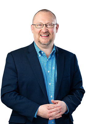 Martin Westwell smiling, wearing a blue shirt, blue jacket and glasses.