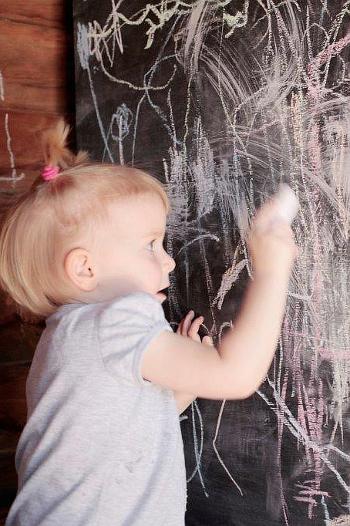 Toddler writing on a chalkboard 