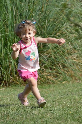 Girl aged three running towards camera