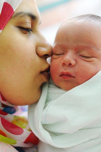Mother kissing her new born baby