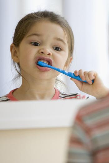 Young girl cleans her teeth in the mirror