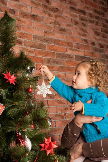Young girl hanging a star on a Christmas tree