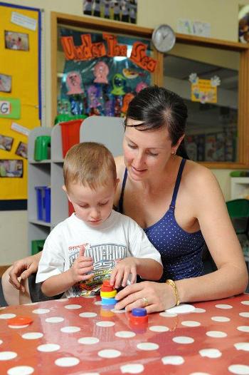 Child stacking blocks with woman