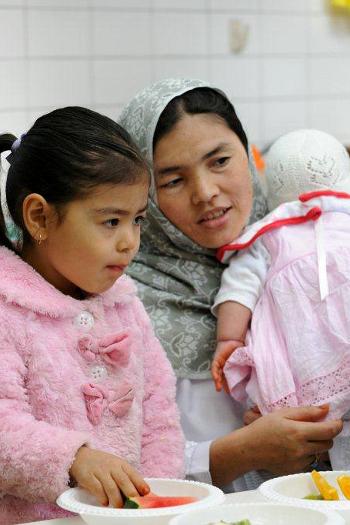 Young girl eating watermelon with her mother