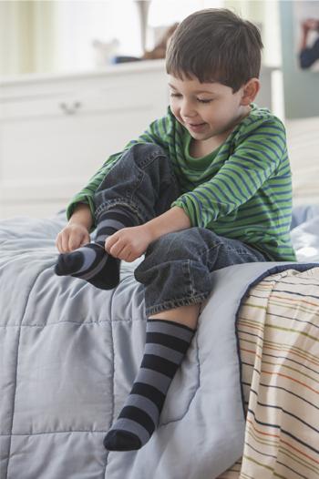 Young boy putting socks on