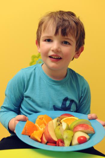 Young boy holding a plate of fruit