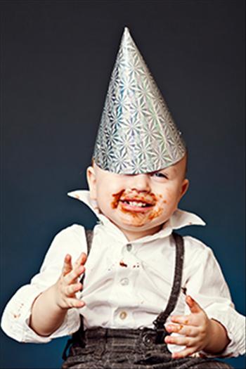 Boy toddler with chocolate cake on his hands and face. 