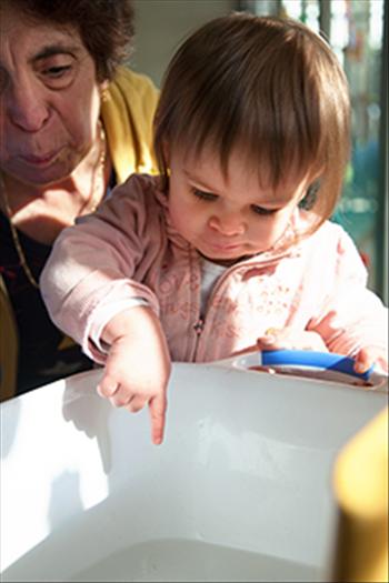 Young girl testing the temperature of the bath with adult