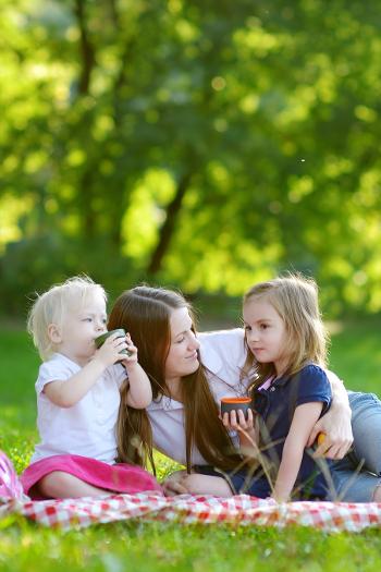 Mother and two young girls sitting in the park