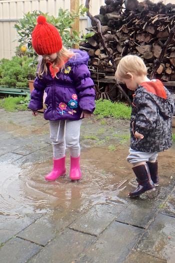 Young boy and girl playing in puddles