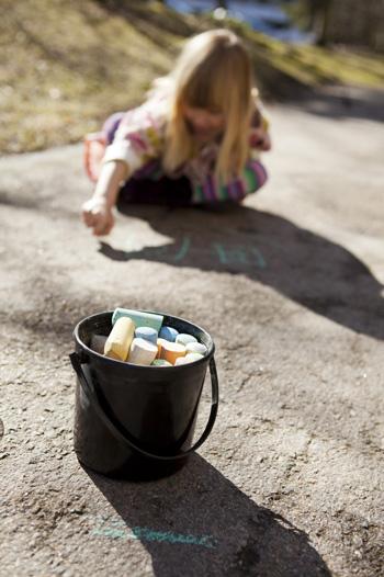 Young girl writing on the road with chalk