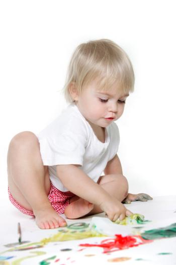 Young girl finger painting to make wrapping paper