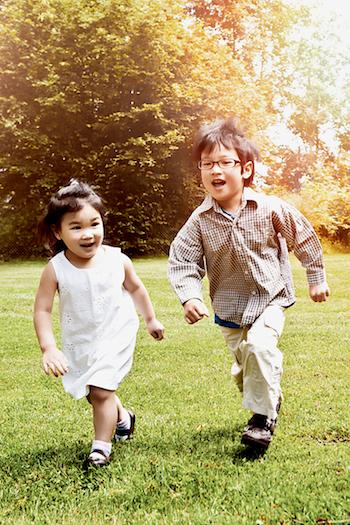 Two children, a boy and a girl, running in the park