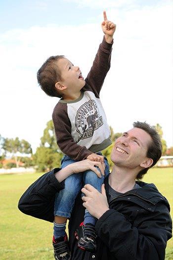 Young boy pointing up at the sky on the shoulder of an adult