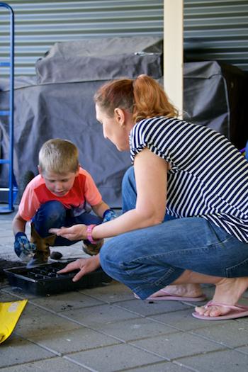 Woman helping young buy plant a seed