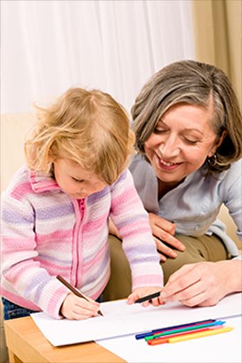 Young girl colours cards while woman watches