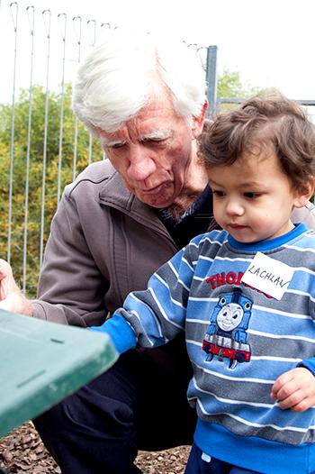 Young boy placing recycling in the bin assisted by an adult