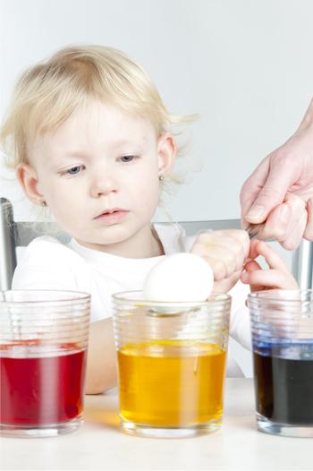 Young girl decorating boiled eggs with mother