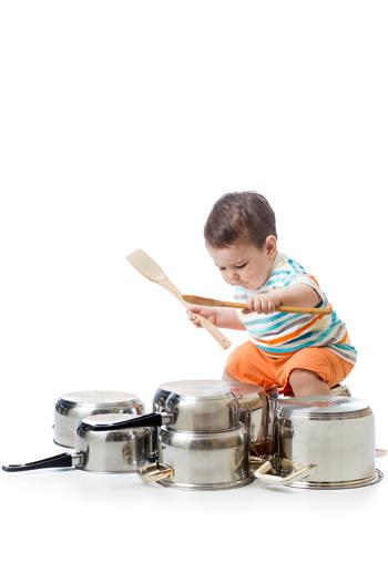 Toddler playing with pots and a wooden spoon