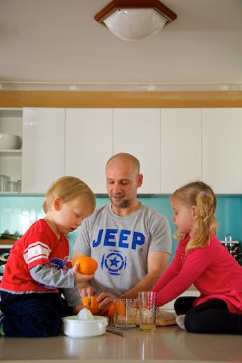 Father squeezing orange for juice with children