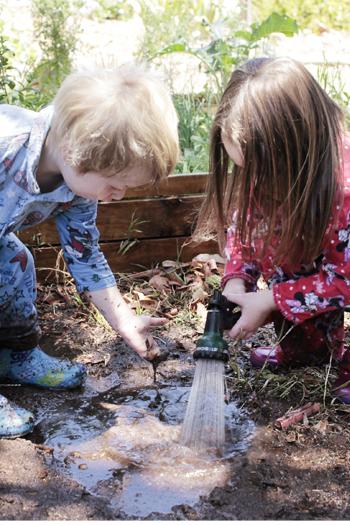 Young boy and girl playing with a hose