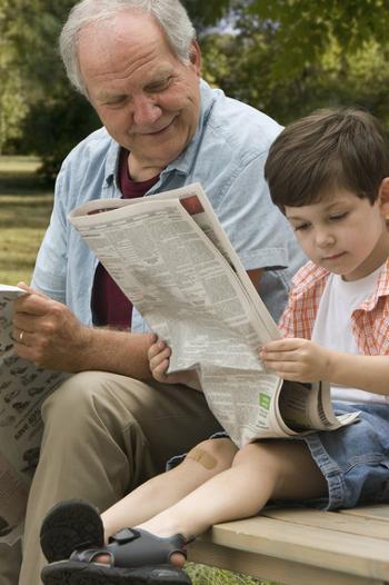 Boy reading paper with grandfather