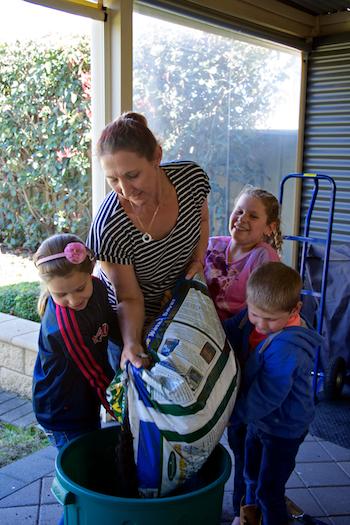 Adult and three children pouring soil into a pot