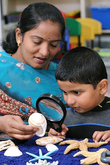 Woman and young boy looking at shells with a magnifying glass 