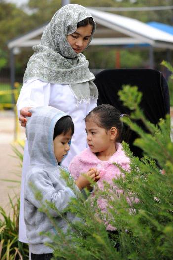 Mother and two children in the garden touching leaves