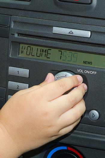 A hand turning up the volume in the car
