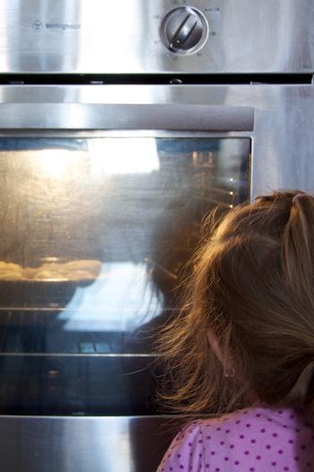 Child watching food cook in the oven