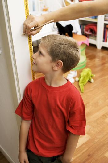 Adult measuring young boys height on a wall