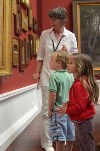 Young girl and boy looking at a painting with an adult